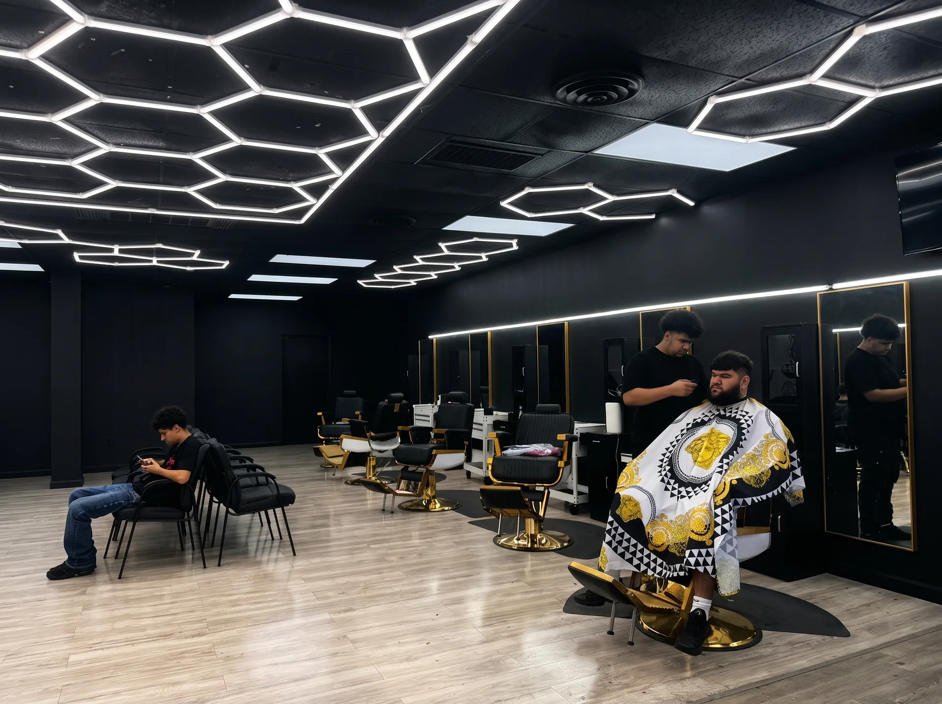 Inside Bankz BarberHouse — hexagon lights and gold chairs